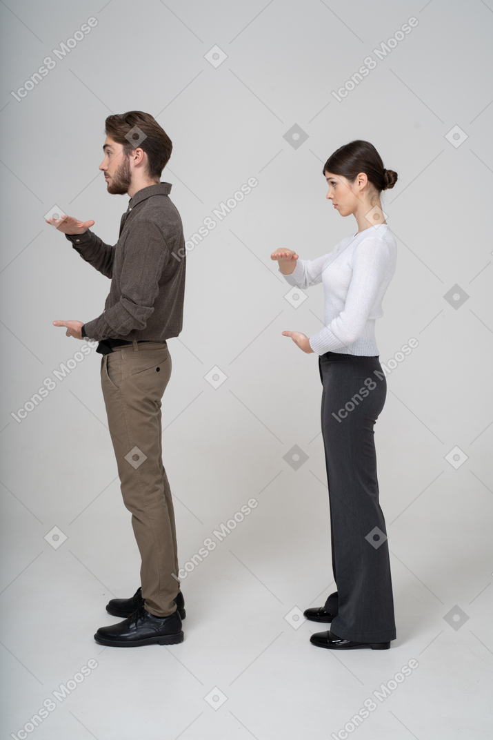 Vue latérale d'un jeune couple en vêtements de bureau montrant la taille de quelque chose
