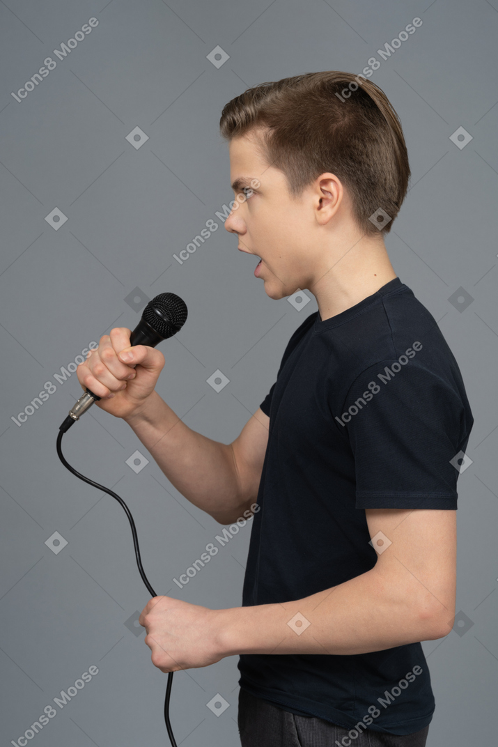 Young man speaking into a microphone sideways to a camera