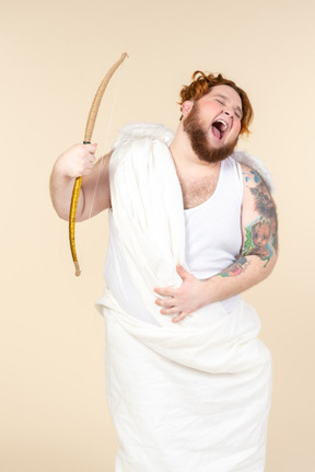 Laughing big guy dressed as a cupid holding bow