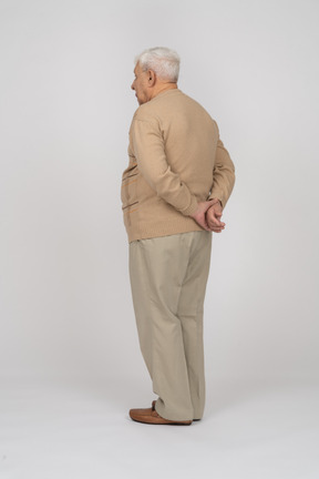 Vista traseira de um velho em roupas casuais em pé com as mãos atrás das costas