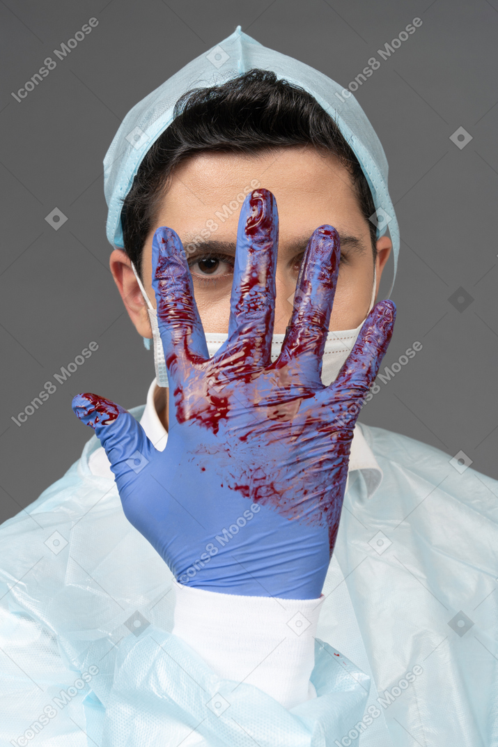 Médico mostrando sua luva coberta de sangue