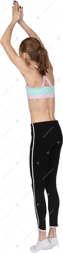 Dreiviertel-rückansicht eines jugendlichen mädchens in der sportbekleidung, die auf zehenspitzen steht und hände hebt