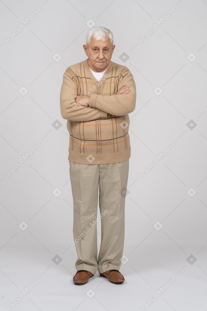 Vista frontal de um velho em roupas casuais em pé com os braços cruzados