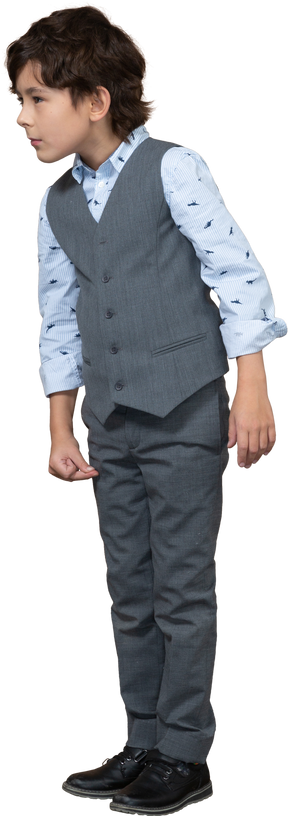 Вид спереди на симпатичного мальчика в сером костюме, с интересом смотрящего на что-то