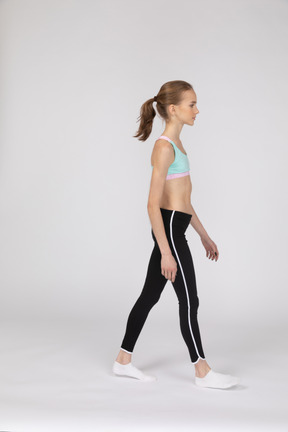 Vista lateral de una jovencita en ropa deportiva caminando