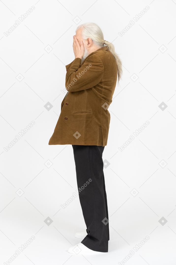Side view of an old man covering his face