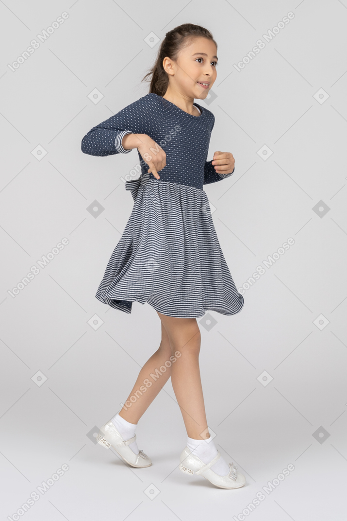 Vista de tres cuartos de una niña bailando y saltando graciosamente
