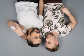互いに近くの床に横たわっている2人の若い白人男性の平らな横たわり