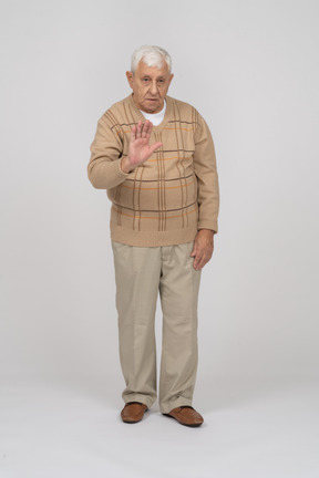 一位穿着休闲服的老人的正面图显示停止手势