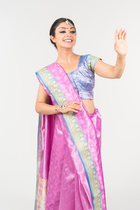 Young indian woman in purple sari waving with a hand