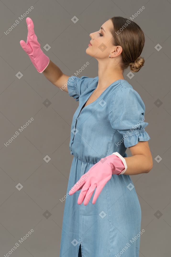 Beautiful young woman moving her arms while wearing cleaning gloves