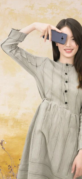 A woman in a grey dress is taking a picture with her phone