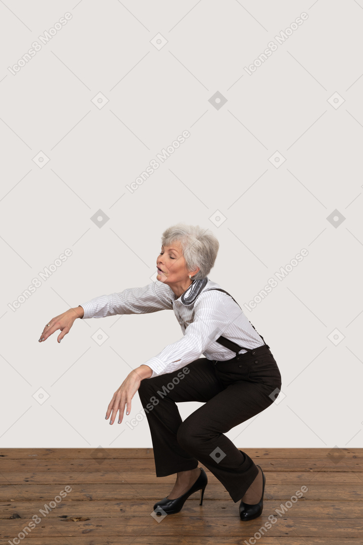 Three-quarter view of a squatting old lady outstretching her hands