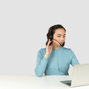 A woman in a headset sitting at a table with a laptop