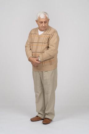 Front view of an old man in casual clothes standing with crossed hands