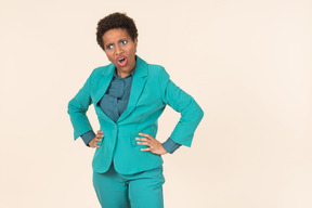 Black woman with a short haircut, wearing all blue, standing against a plain pastel background, looking emotional