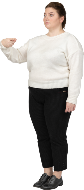 Женщина больших размеров в белом свитере показывает пальцем