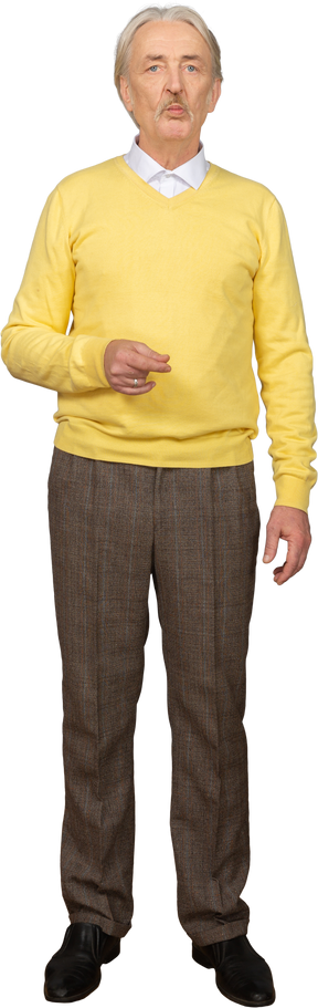 Vorderansicht eines verwirrten alten mannes in einem gelben pullover, der hand hebt und kamera betrachtet