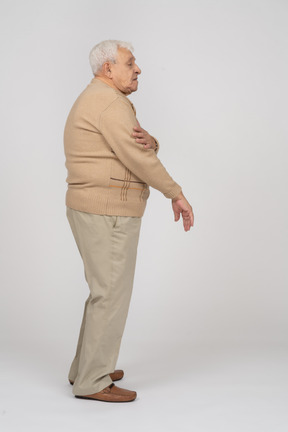 Side view of an old man standing with hand on arm