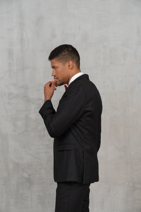 Side view of a man in black suit thinking