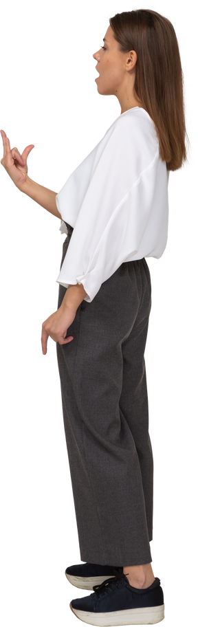 Side view of a young lady in office clothing showing rock gesture
