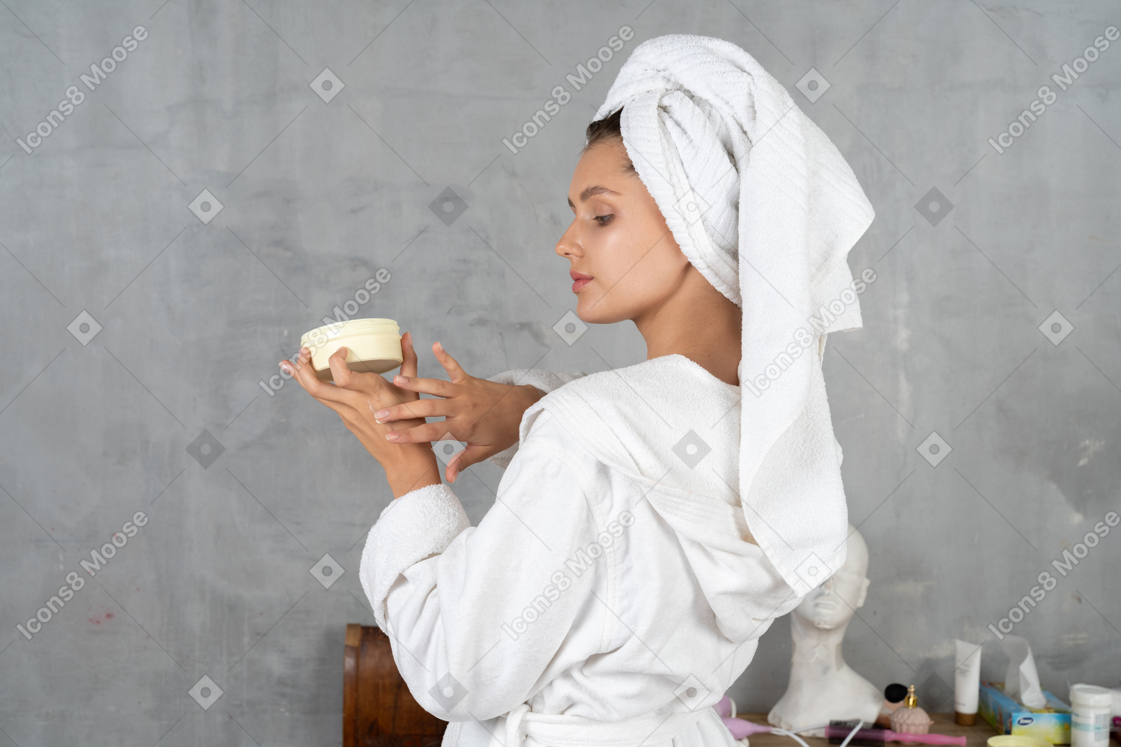 Vista trasera de una mujer en bata de baño aplicando crema de manos