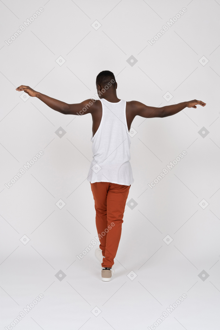Back view of man walking with spread arms