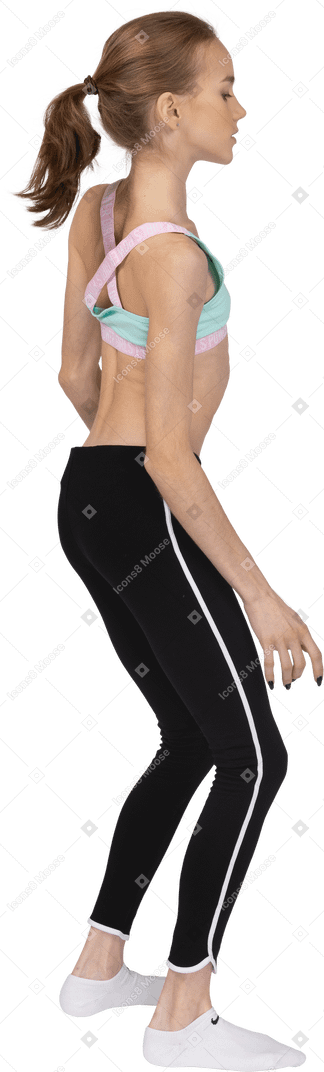 Vista traseira de três quartos de uma adolescente em roupas esportivas inclinando os ombros