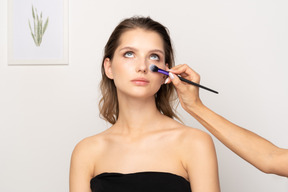 Vista frontal de um maquiador aplicando pó facial em uma modelo feminina