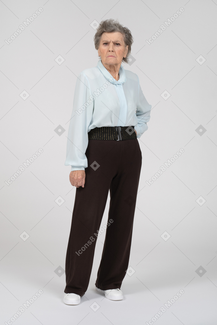 一位老妇人的正面图，一只手放在她的臀部皱着眉头