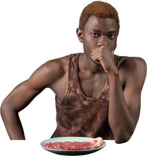 テーブルに座っている思いやりのある若いアフロ男の正面図
