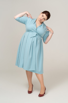Front view of a woman in blue dress posing with hands on shoulders