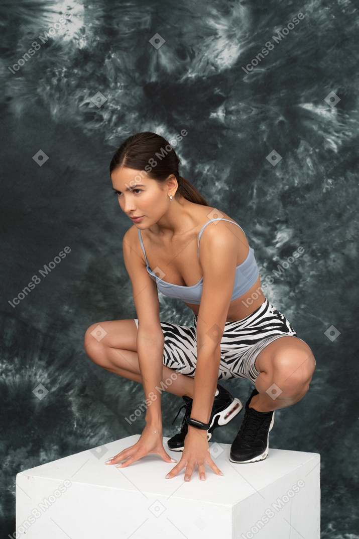 Una atleta femenina sentada a cuatro patas mirando seriamente a un lado