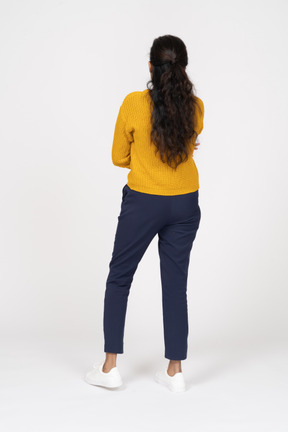 Vista posteriore di una ragazza in abiti casual in posa con le braccia incrociate