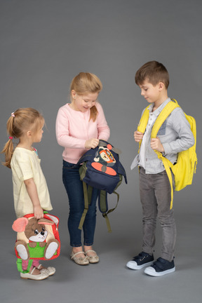 Tres niños con lindas mochilas y juguetes.