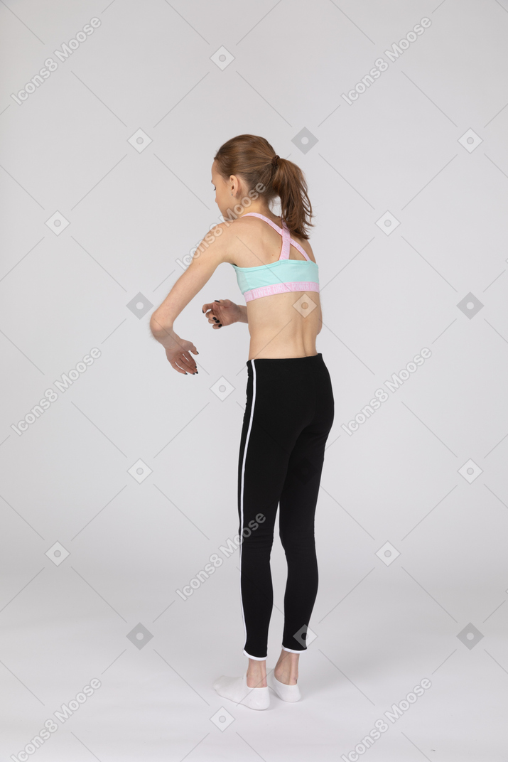 Three-quarter back view of a weak teen girl in sportswear leaning forward while gesticulating