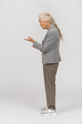 Side view of an old lady in suit pointing with hand