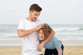 A man messing up a woman's hair on the beach