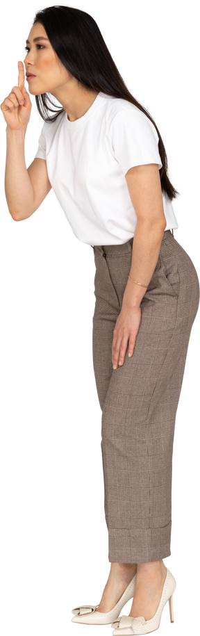Vista de tres cuartos de una señorita en calzones y camiseta mostrando un gesto de silencio