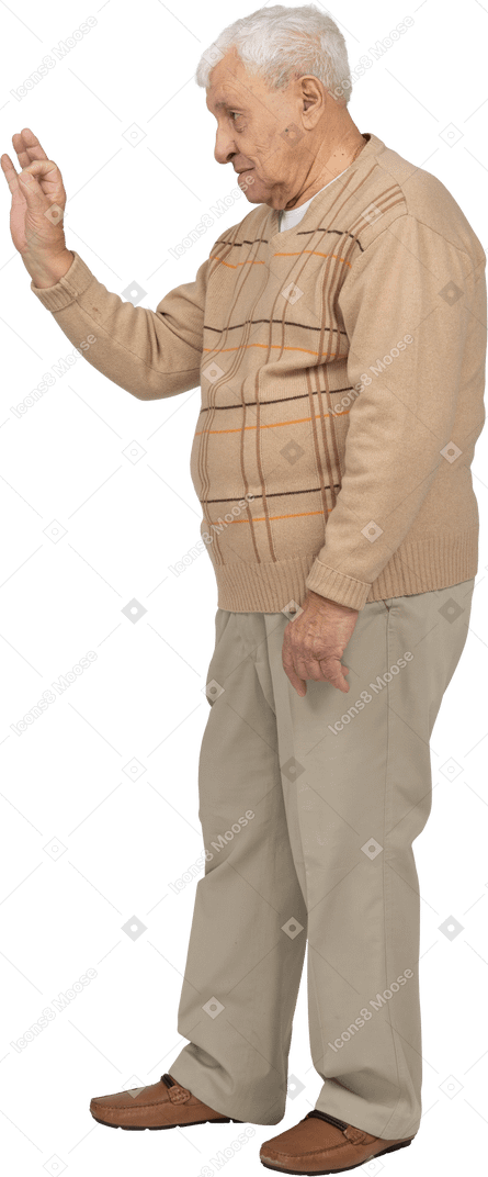 Vista lateral de um velho em roupas casuais, mostrando sinal de ok
