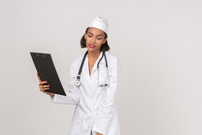 Atraente médico feminino olhando através de alguns documentos