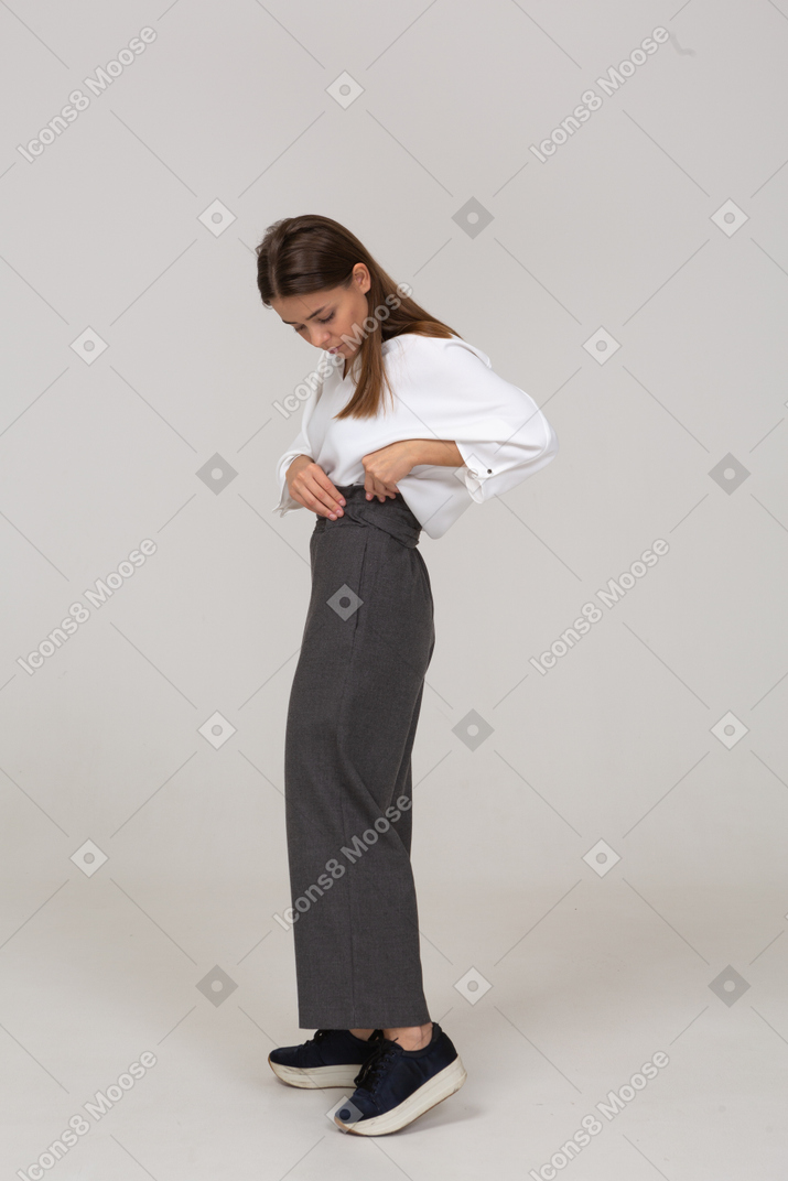 Side view of a young lady in office clothing adjusting her pants