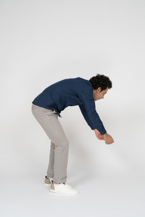 Side view of a man in casual clothes bending down