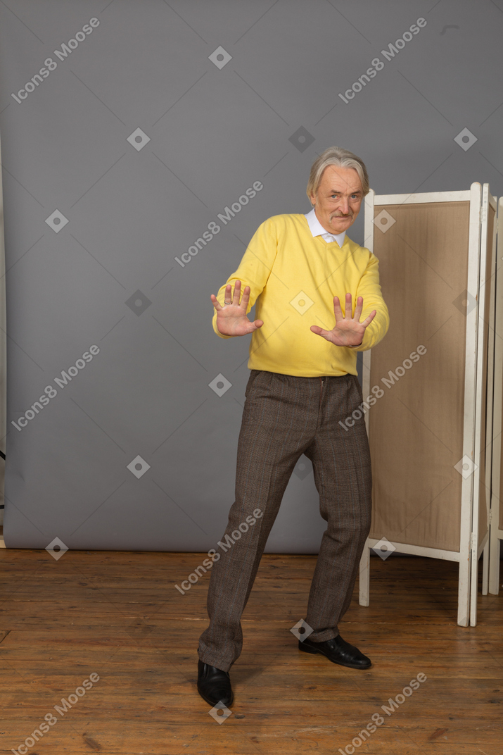 Vue de face d'un vieil homme timide souriant tendant les mains