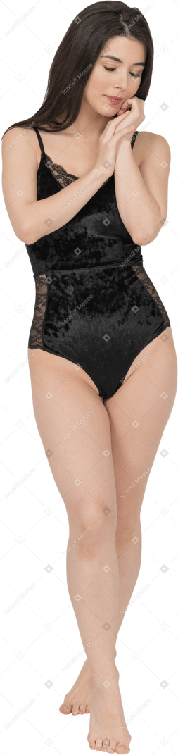 Femme tendre en lingerie noire posant avec les mains à côté du visage et les yeux fermés