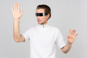Young man in futuristic eyewear touching something invisible