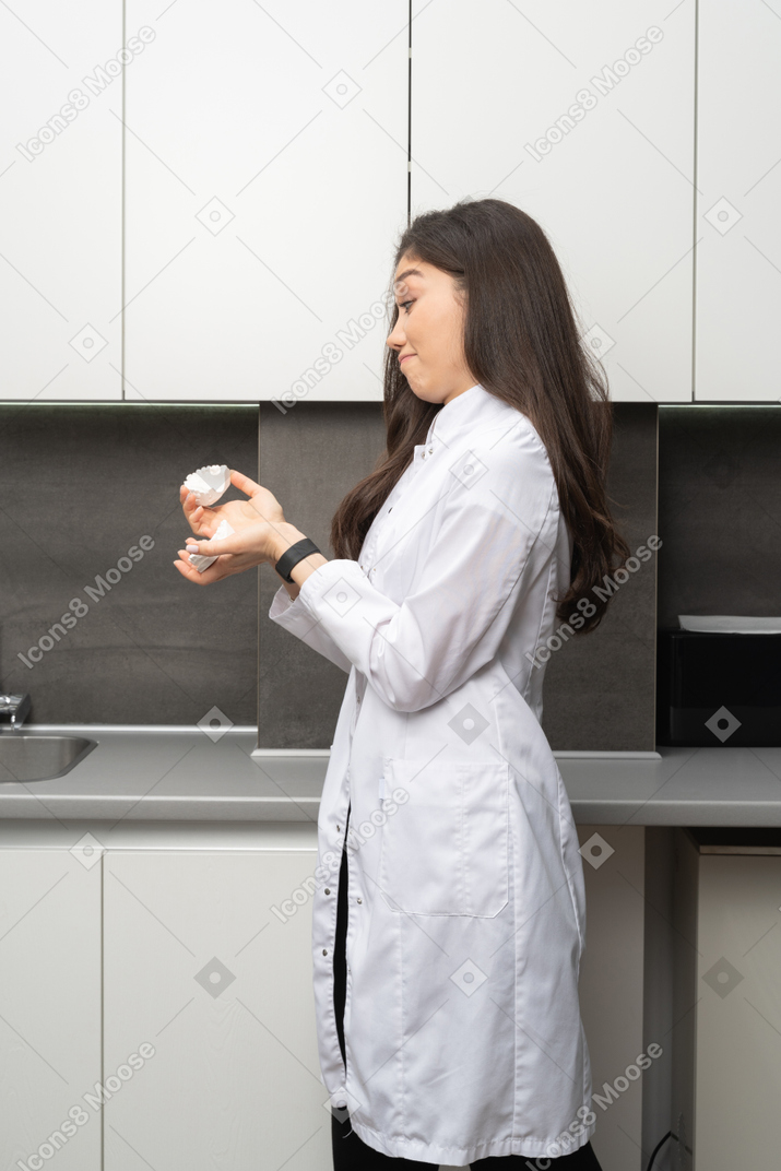 Side view of a puzzled female dentist holding jaws prototype