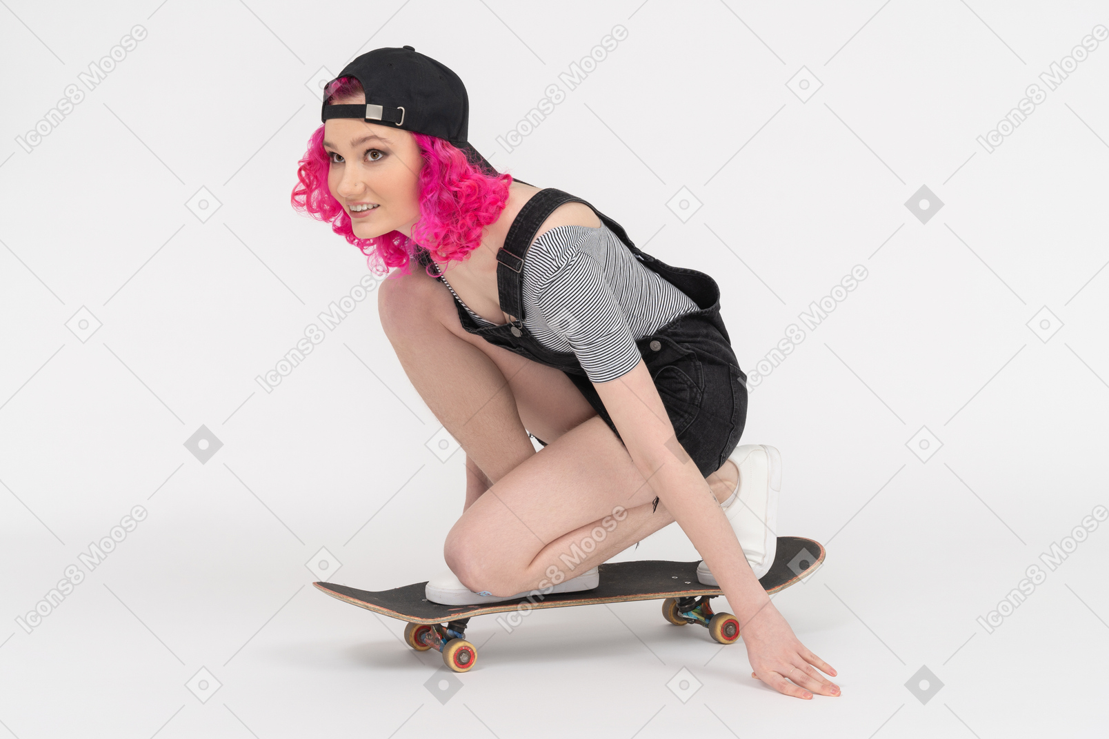 Cheerful girl riding a skateboard down on her knees