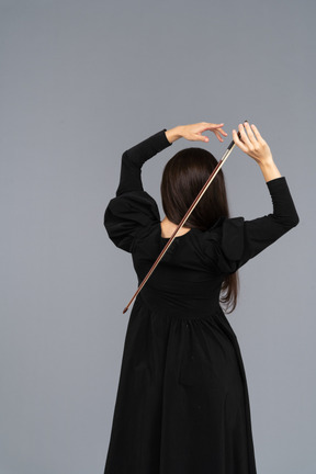 Back view of a young lady in black dress holding the bow behind