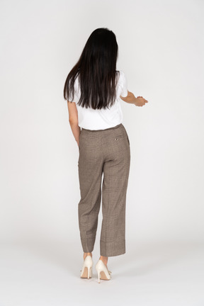 Three-quarter back view of a young lady in breeches and t-shirt outstretching her hand